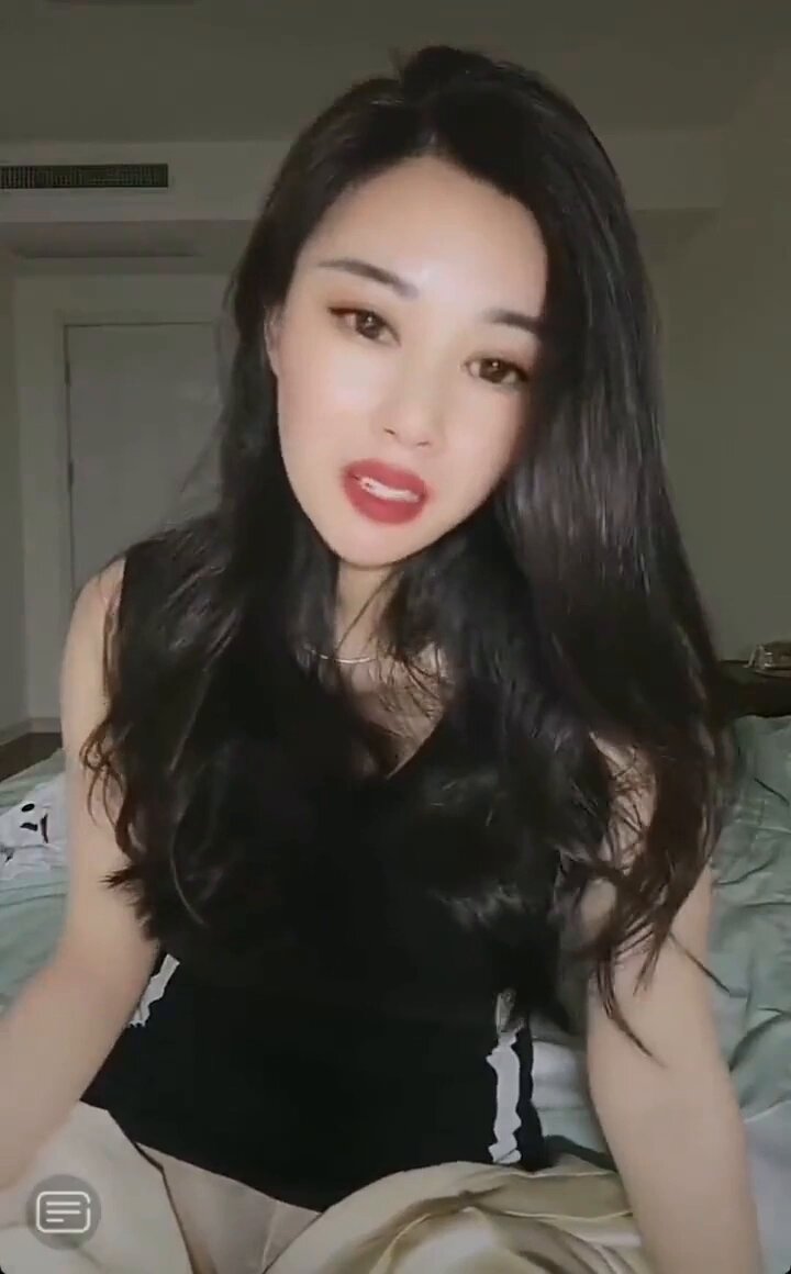 Long-haired beauty in black stockings teasing on the bed — red lips and a provocative tongue