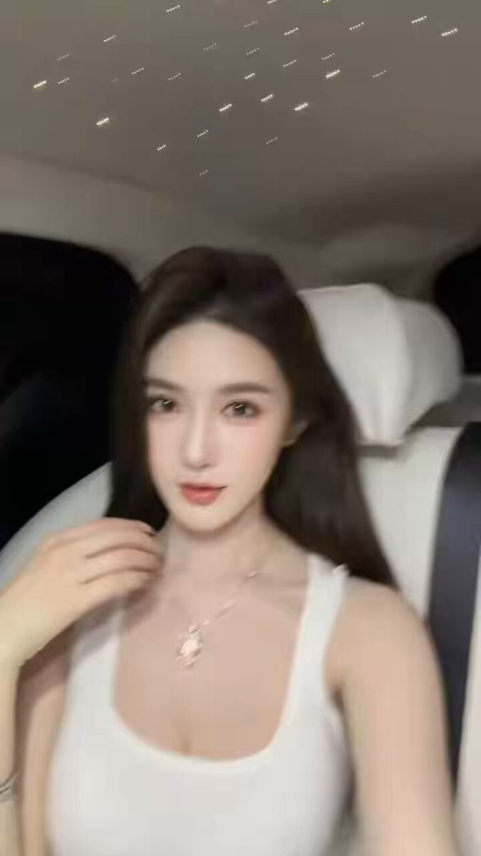 Busty beauty tempts with a selfie inside a luxury car! Deep cleavage in a white tank top steals the heart
