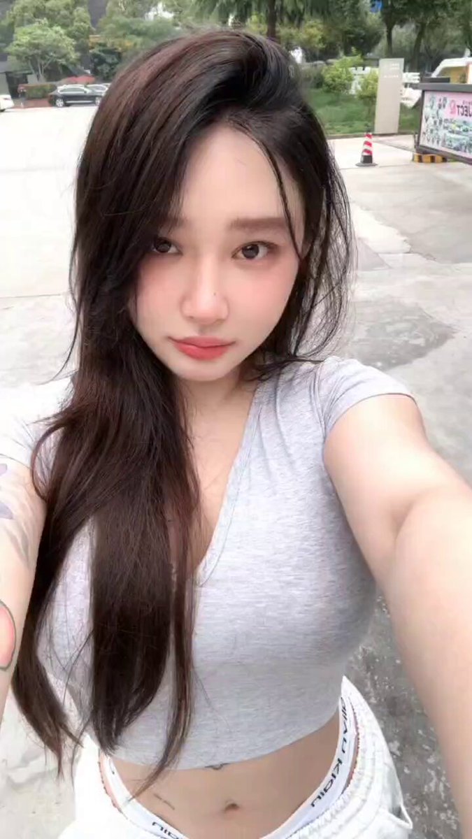 長髪美女が谷間と腹筋を披露！グレーのローVネックTシャツに白パンツ、野外セルフィーで超色っぽい