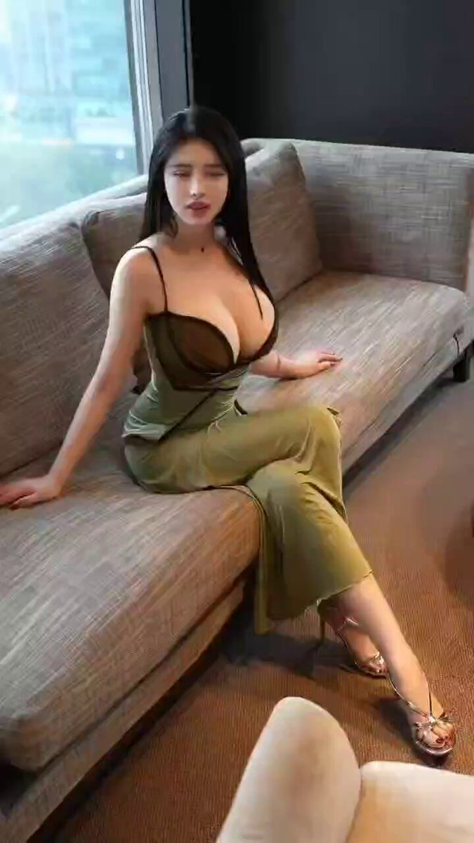 緑のドレスの爆乳美女がソファで誘惑 — 深Vで揺れる巨乳、ハイヒールで脚を組む