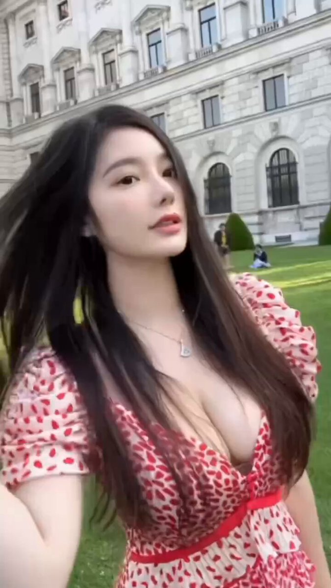Busty beauty in front of a European castle in a plunging red dress — her huge breasts sway so seductively!