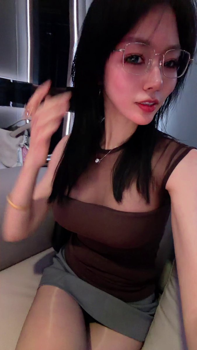 Glasses-wearing dark-haired beauty tempts on the sofa! Sheer top reveals huge breasts, short skirt and perky butt are ultra seductive